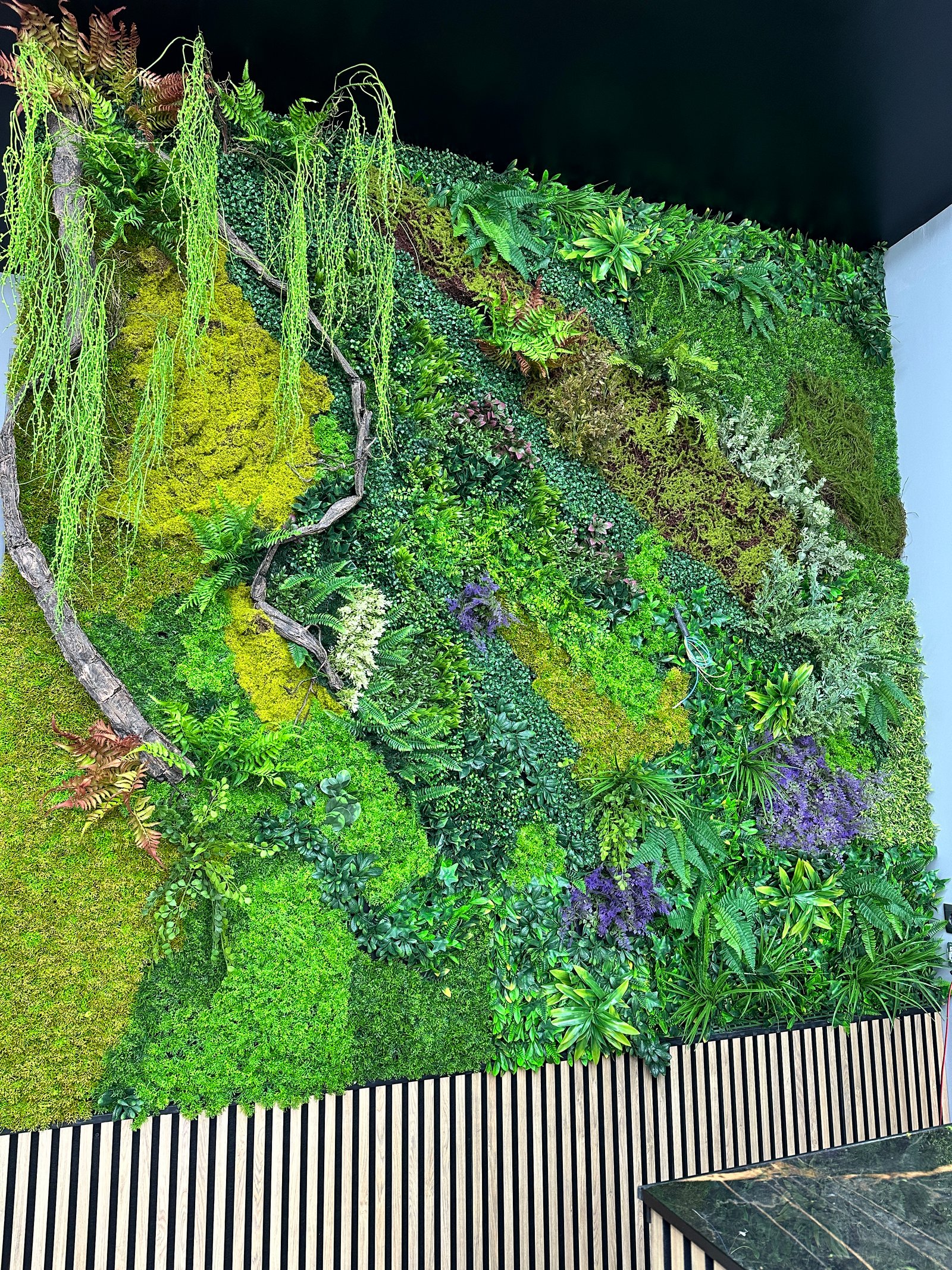 Detalle de plantas artificiales y ramas decorativas en pared vegetal