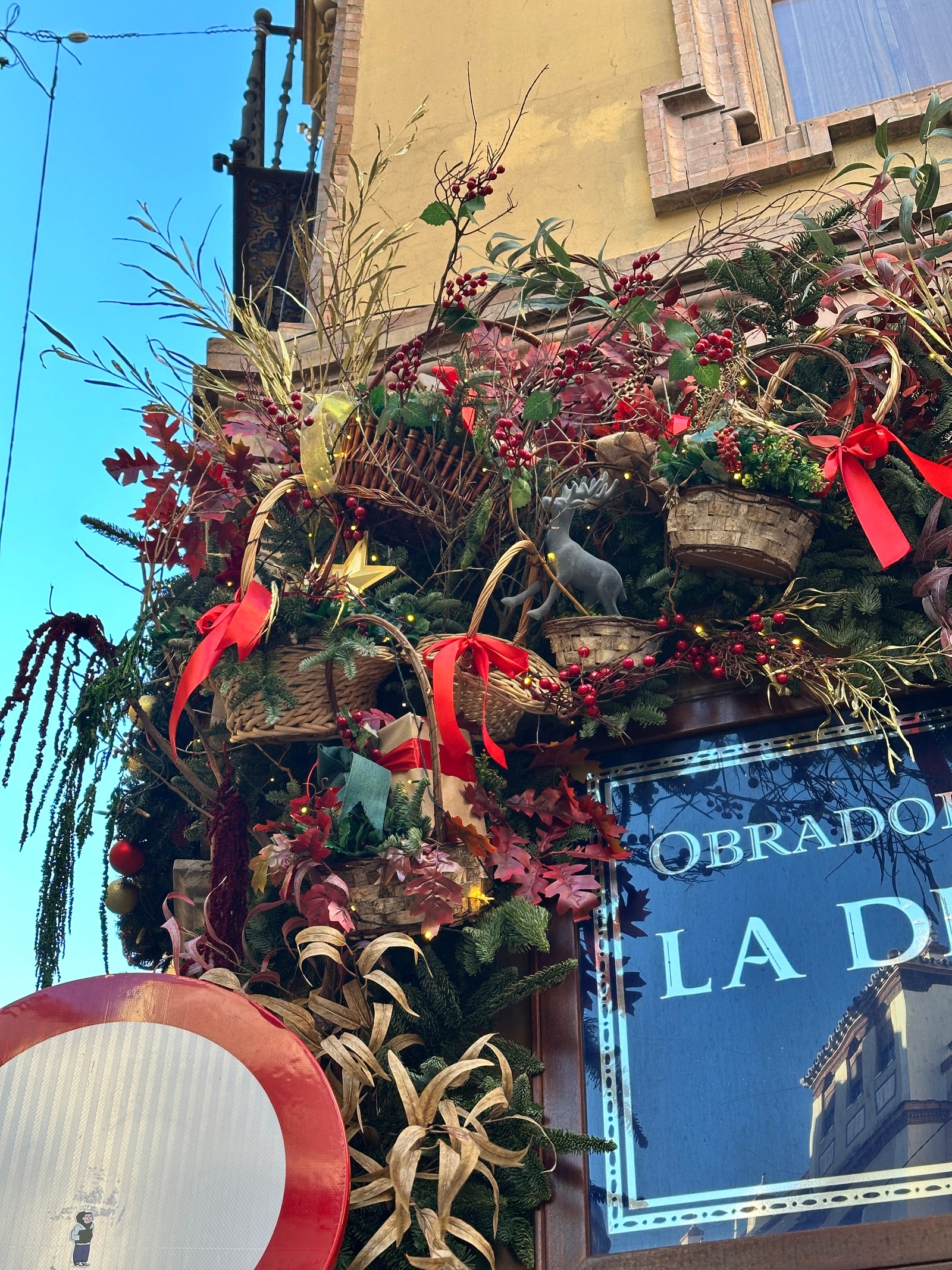 Detalles de ramas, frutos rojos y cintas navideñas en fachada decorada