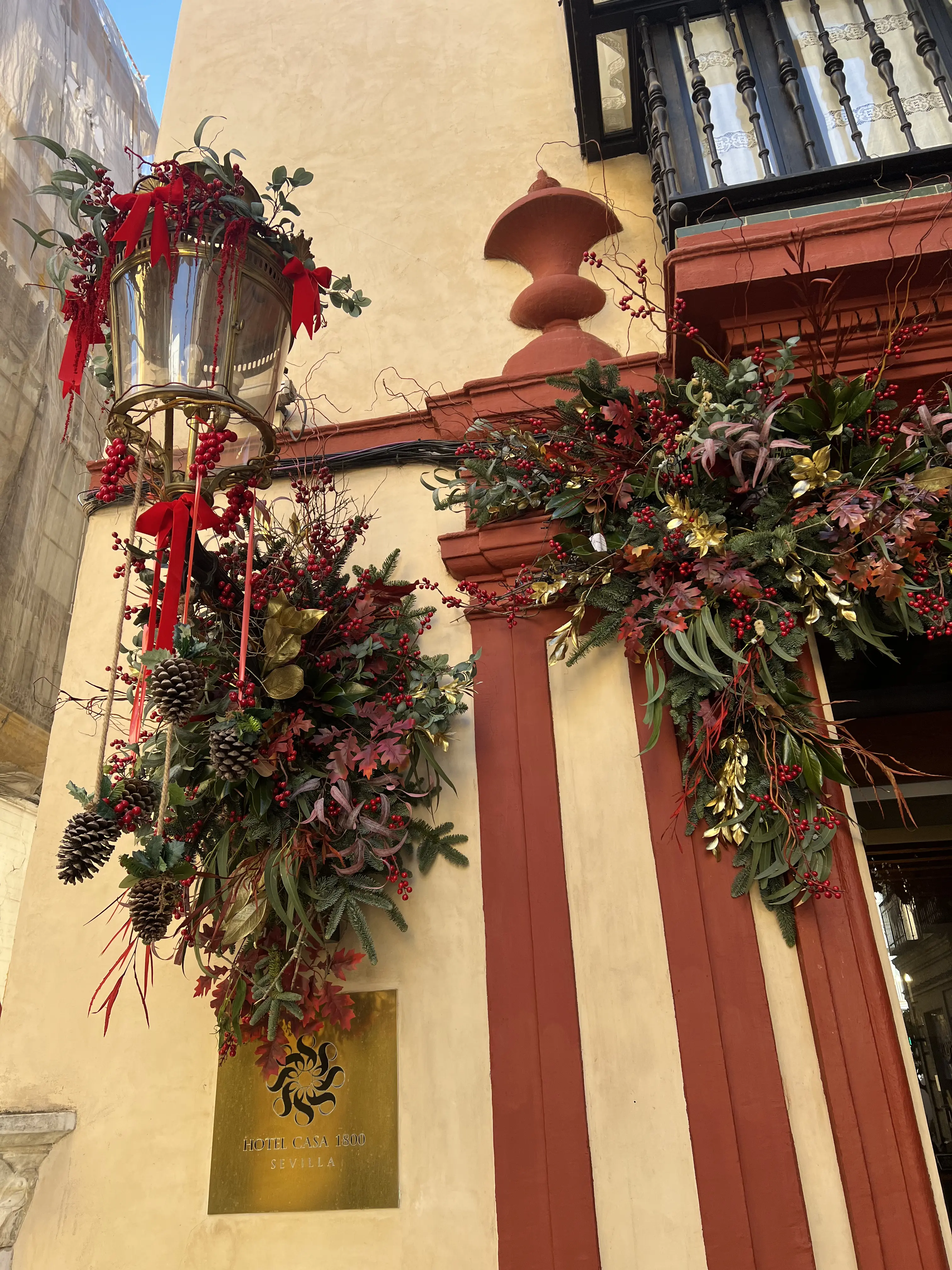Decoración vegetal navideña con frutos rojos y piñas en entrada de hotel