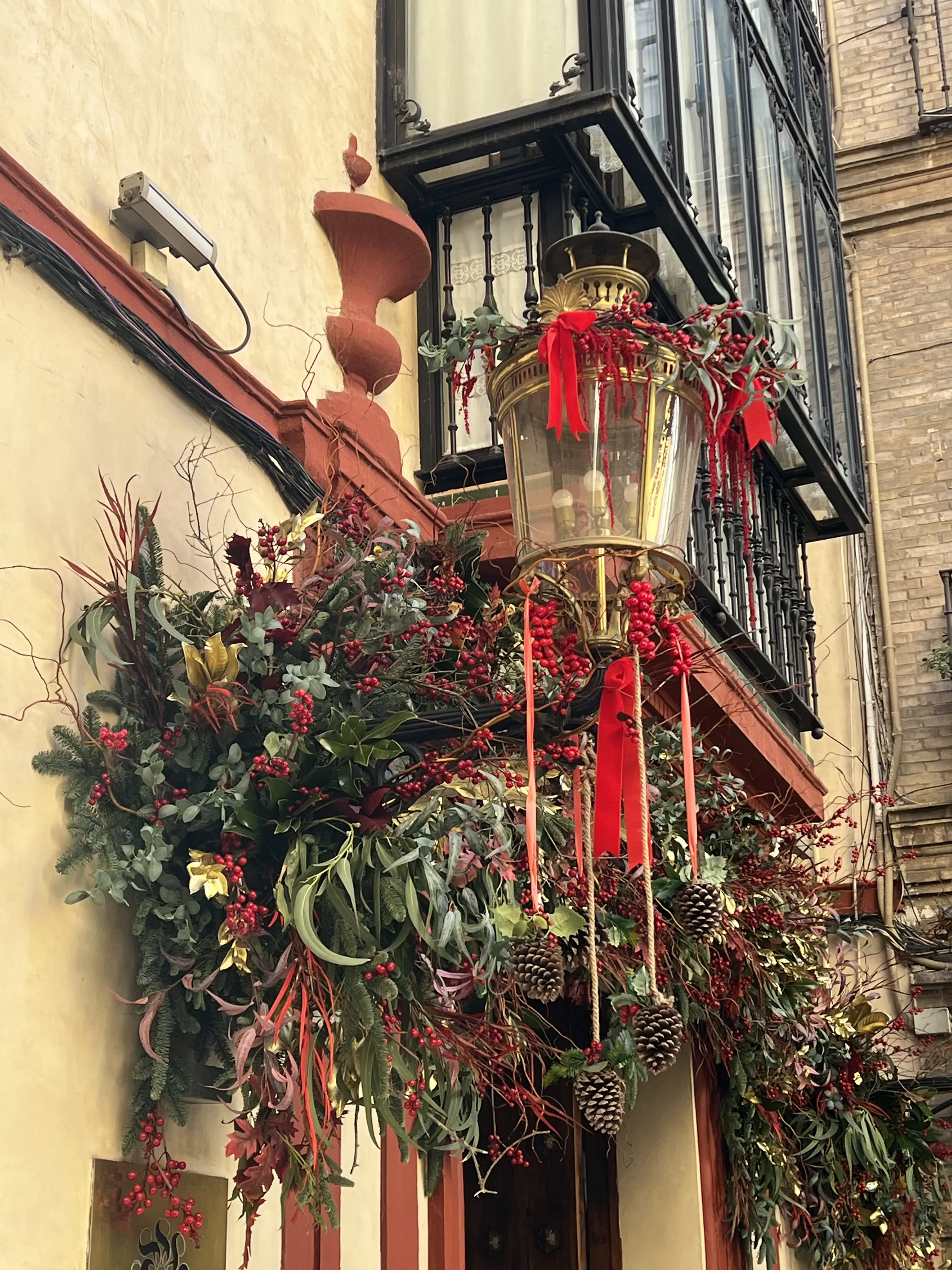 Decoración navideña en farol exterior con cintas y vegetación
